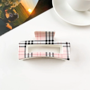 Detail of pink plaid square hair claw clip with cutout design on white background