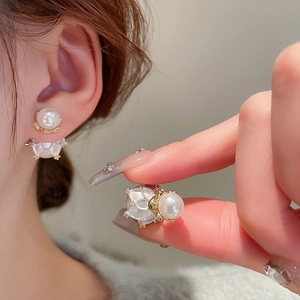 Close-up of pearl stud earring with gold plating and cubic zirconia on a model