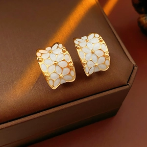 Macro de boucles d'oreilles C en forme de fleurs dorées avec pétales blancs et lumière