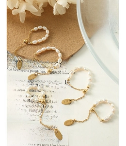 Détail de la bague ajustable en perles plaquée or 18K avec gravure K18 sur le pendentif