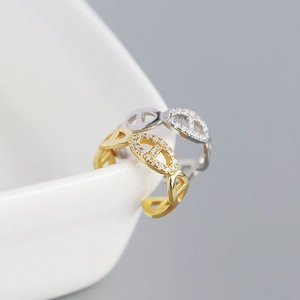 Detailed shot of gold and silver chain link rings with pavé set crystals on a white ceramic bowl