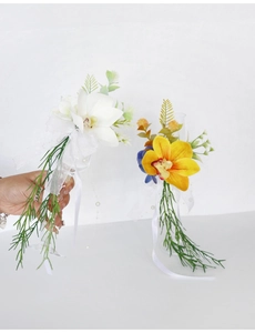 Close-up of white and orange cymbidium orchid wine glass decor with ribbons