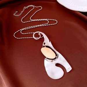 Artistic mixed-tone elephant pendant necklace with brushed metal finish on silk backdrop