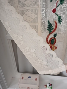 Close-up of cream lace curtain featuring intricate floral embroidery and scalloped edges