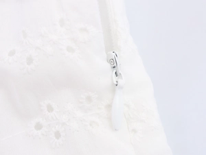 Close-up of white hollow embroidery texture and concealed invisible zipper on midi dress