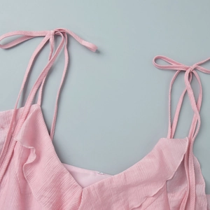 Detailed view of pink V-neck strap top with ruffle trim and pleated fabric texture