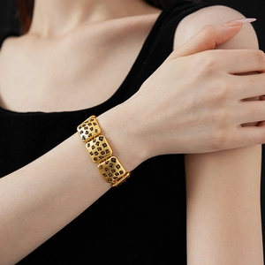 Close-up of vintage golden bracelet with floral patterns and red and black gemstones