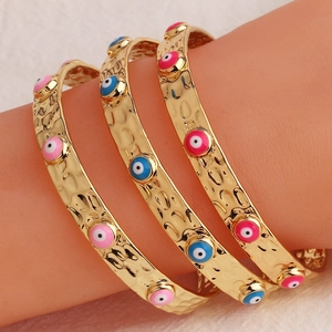 Dettaglio di tre braccialetti con occhio placcati in oro 18K con finitura testurizzata