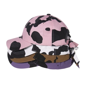Detailed comparison of baseball caps in pink, white, brown and purple cow print patterns