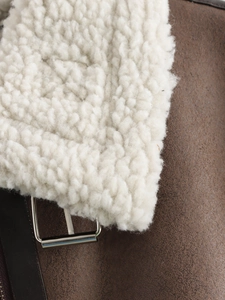 Detail of brown faux suede vest with creamy sherpa lining and silver metal buckle