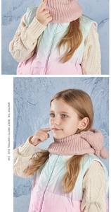 Detail of pink knitted scarf with pom-poms on a child wearing a gradient puffer vest