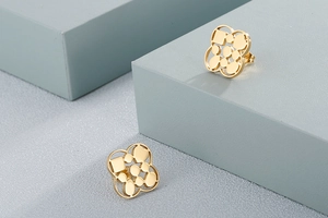 Detail of gold geometric hollow flower earrings on blue minimalist display stand