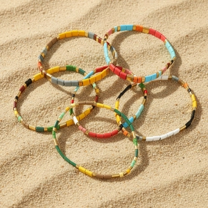 Set of 7 bohemian Tila bead bracelets with colorful enamel on a sunny beach background