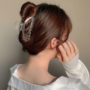 Minimalist large transparent hair claw clip for women holding a neat hair bun style