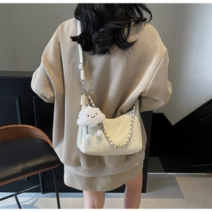 Detail of white woven PU leather bag with silver chain strap and plush cloud pendant