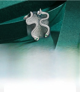Detail of S925 silver snake earrings with pavé zircons and green stone eyes