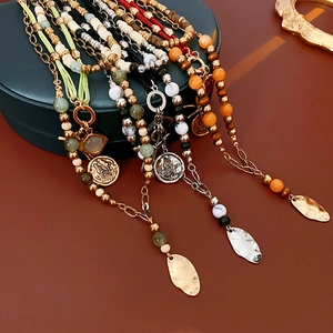 Detail of layered beaded necklaces with metallic pendants and bow vintage style charm