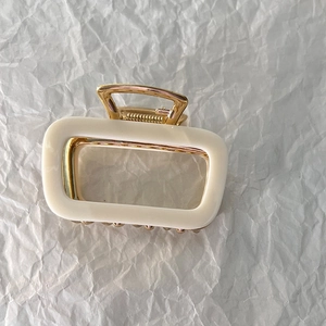 Top view of a cream rectangular hollow hair claw clip with golden metal inner structure