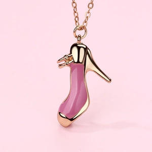 Dettaglio del ciondolo a tacco alto in oro rosa con smalto rosa su sfondo rosa tenue