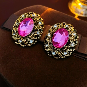 Close-up of vintage gold oval earrings with a pink gemstone on brown velvet