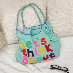 Detail of colorful chenille embroidery on mint green canvas tote bag with woven strap
