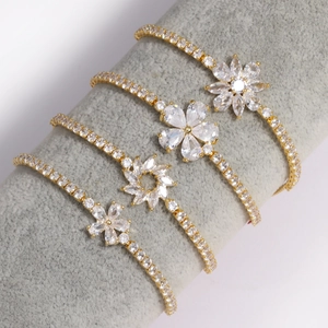 Détail de quatre bracelets fleurs plaqués or avec oxydes de zirconium sur support gris