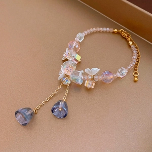 Detail of pink crystal beaded bracelet with white floral accents and lily tassel