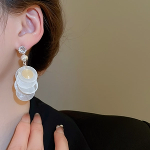 Macro side view of elegant triple-layered shell disc tassel earrings on a model