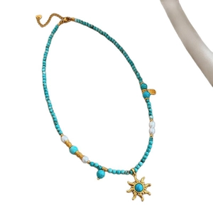 Collier ethnique vintage avec perles turquoise, perles et pendentif soleil sur tissu blanc