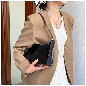 Glossy black PVC shoulder bag shown with a brown suit for a modern fashion look