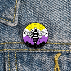 Primer plano de broche de abeja esmaltada no binaria sobre textura de chaqueta vaquera