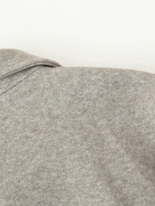 Close-up of the light gray wool fabric texture showing collar and shoulder stitching details