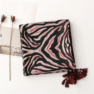 Detail of zebra pattern beach shawl with deep red tassels and soft texture