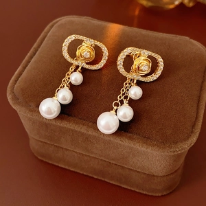 Detail of rose pearl earrings with zircon inlay and gold chain on jewelry box