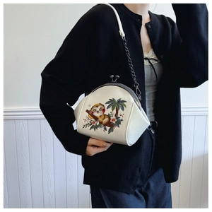 Detail of white embroidered shell bag featuring a sloth pattern and metal chain strap
