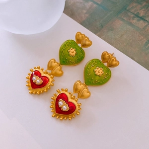 Macro detail of vintage heart earrings with red green enamel and pearl inlays