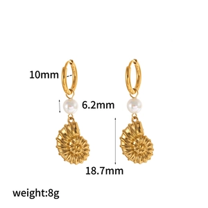 Detail view of gold seashell earrings with 6.2mm pearl and 18.7mm conch pendant