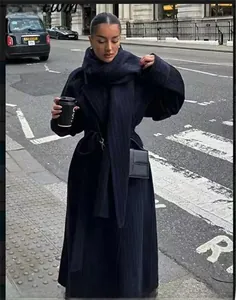 Dettaglio di un cappotto di lana blu navy con sciarpa coordinata e cintura in vita