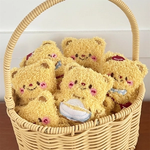 Close-up of cute yellow plush bear charms with embroidered faces in a woven basket