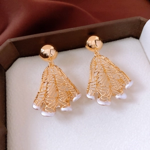 Macro shot of 18K gold plated hollow fan-shaped earrings with pearls in a jewelry box