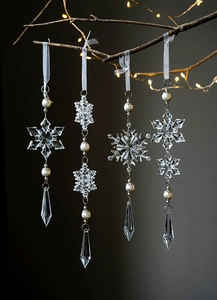 Close-up of clear acrylic snowflake ornaments with pearl accents hanging on a branch