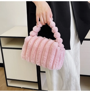 Detail of pink plush handbag featuring soft striped texture and round bead handle