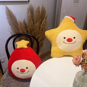 Plüschige Weihnachtsstern- und Geisterkissen mit lächelnden Gesichtern auf einem Stuhl