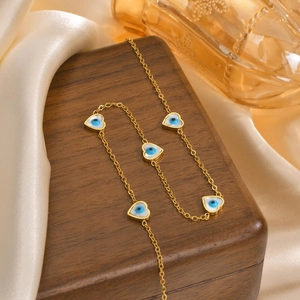 Detail of golden heart-shaped evil eye pendants layered on dark wood jewelry box
