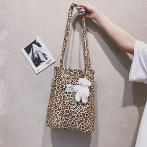 Leopard print canvas tote bag detail with white plush bear charm and sturdy handle