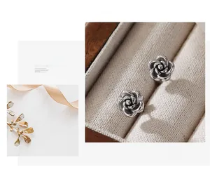 Macro shot of silver rose stud earrings with 3D layered petals on velvet lining