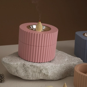 Detail of incense burner with vertical stripes showing lit cone on stone stand