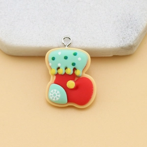 Macro shot of a red and mint green resin Christmas stocking pendant with snow pattern