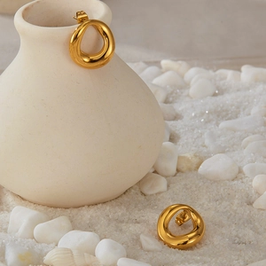 Detail of irregular geometric gold earrings on white ceramic and stone background