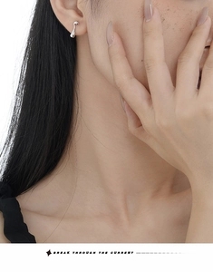Close-up of minimalist silver water drop stud earring worn on a model's ear lobe